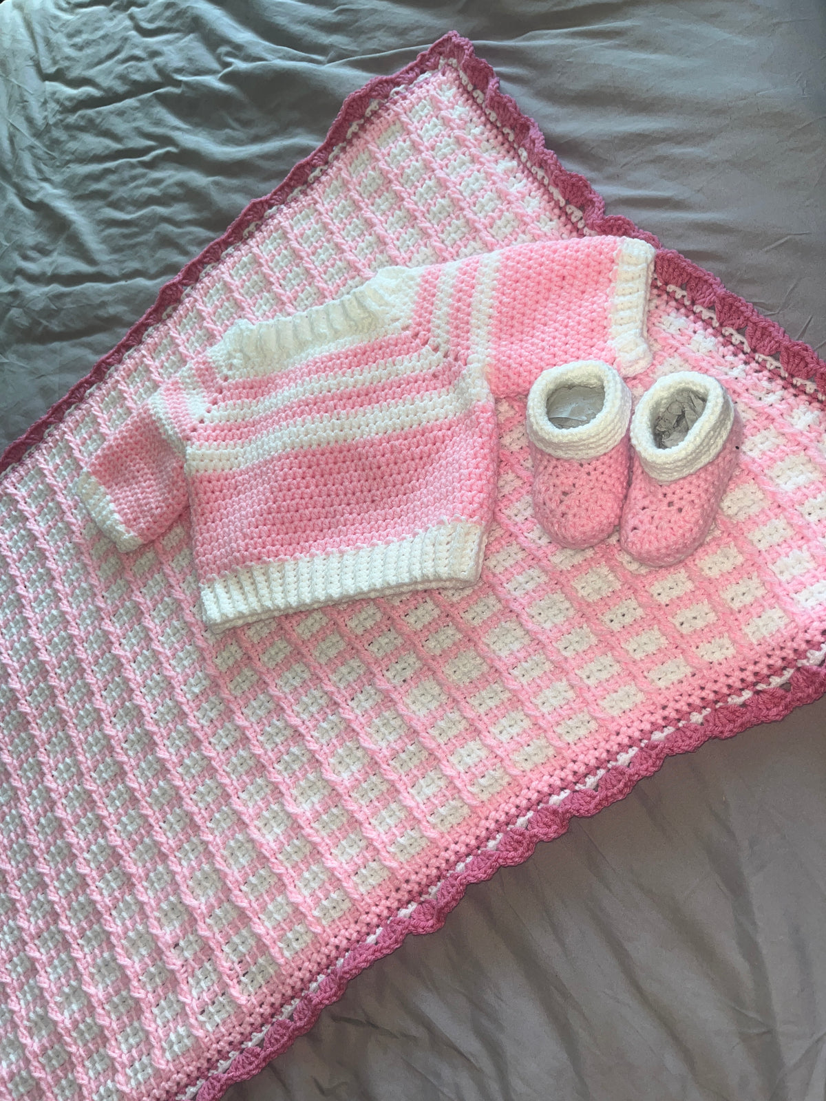 Overhead view of textured baby blanket with coordinating pink-and-white outfit