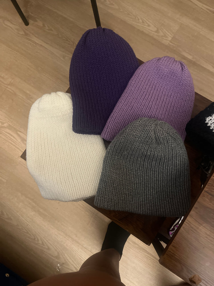 Black and gray striped beanie and white beanie laid flat