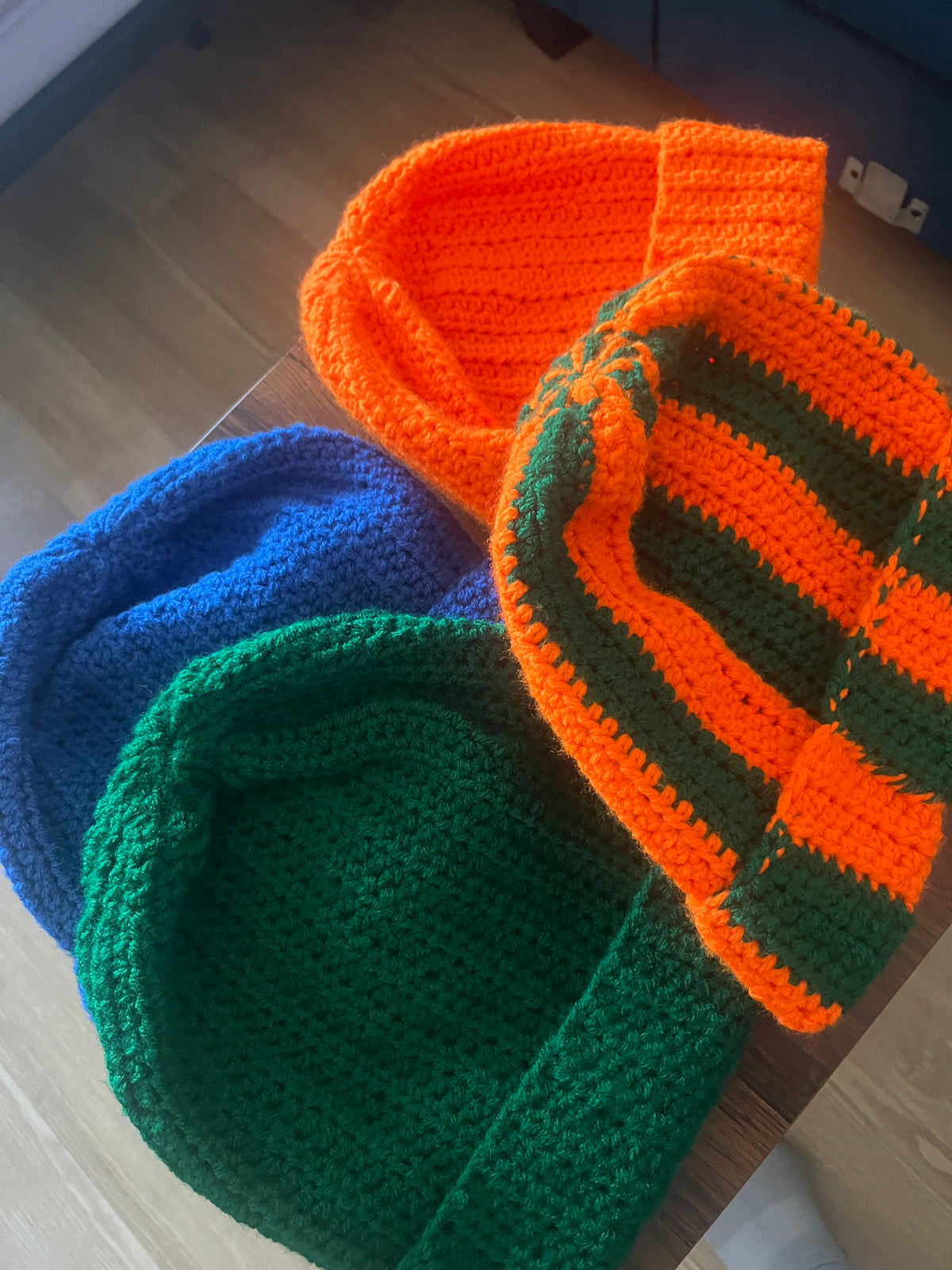 White crochet beanie with multicolor stripes next to a red ribbed crochet beanie