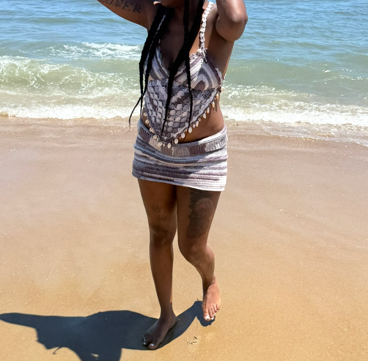 Crochet halter top and mini skirt set worn walking along the shoreline